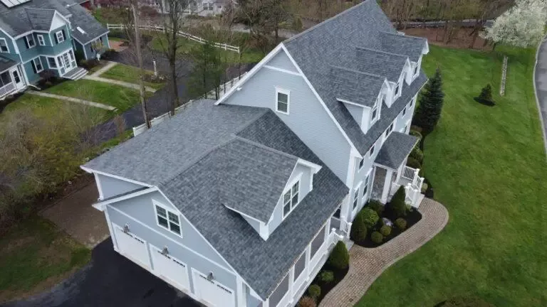 Aerial view of a gray house with a landscaped yard and driveway.